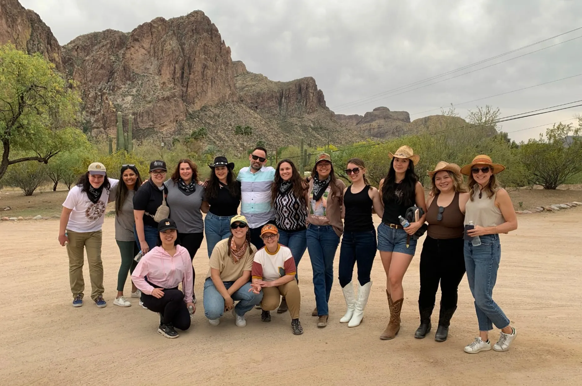 Beets Hospitality team group photo in the desert with rugged mountain cliffs and cacti in the background