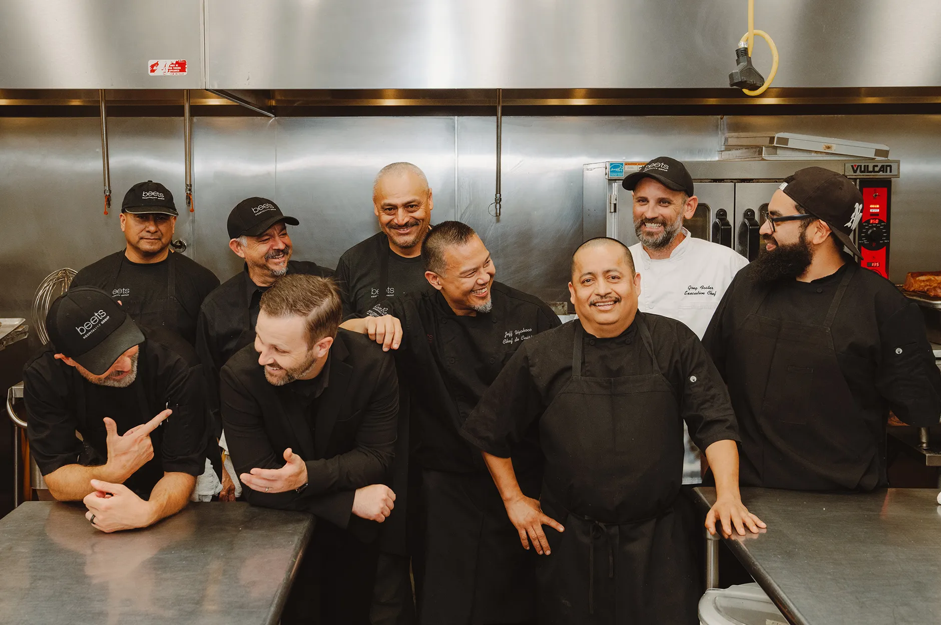 Kitchen crew laughing and joking together in the commercial kitchen after service