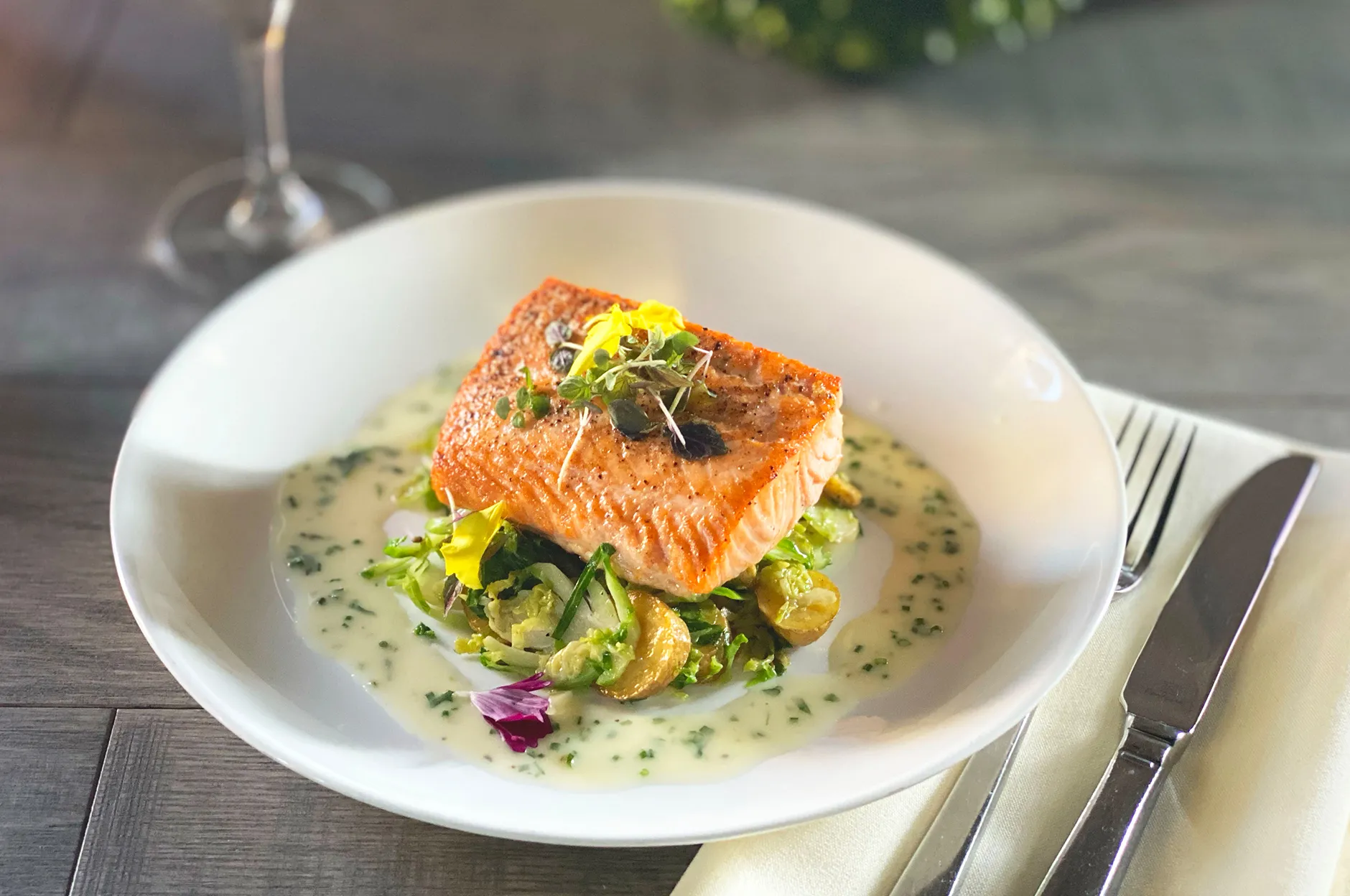 Pan-seared salmon fillet over Brussels sprouts in a herb cream sauce on a white plate