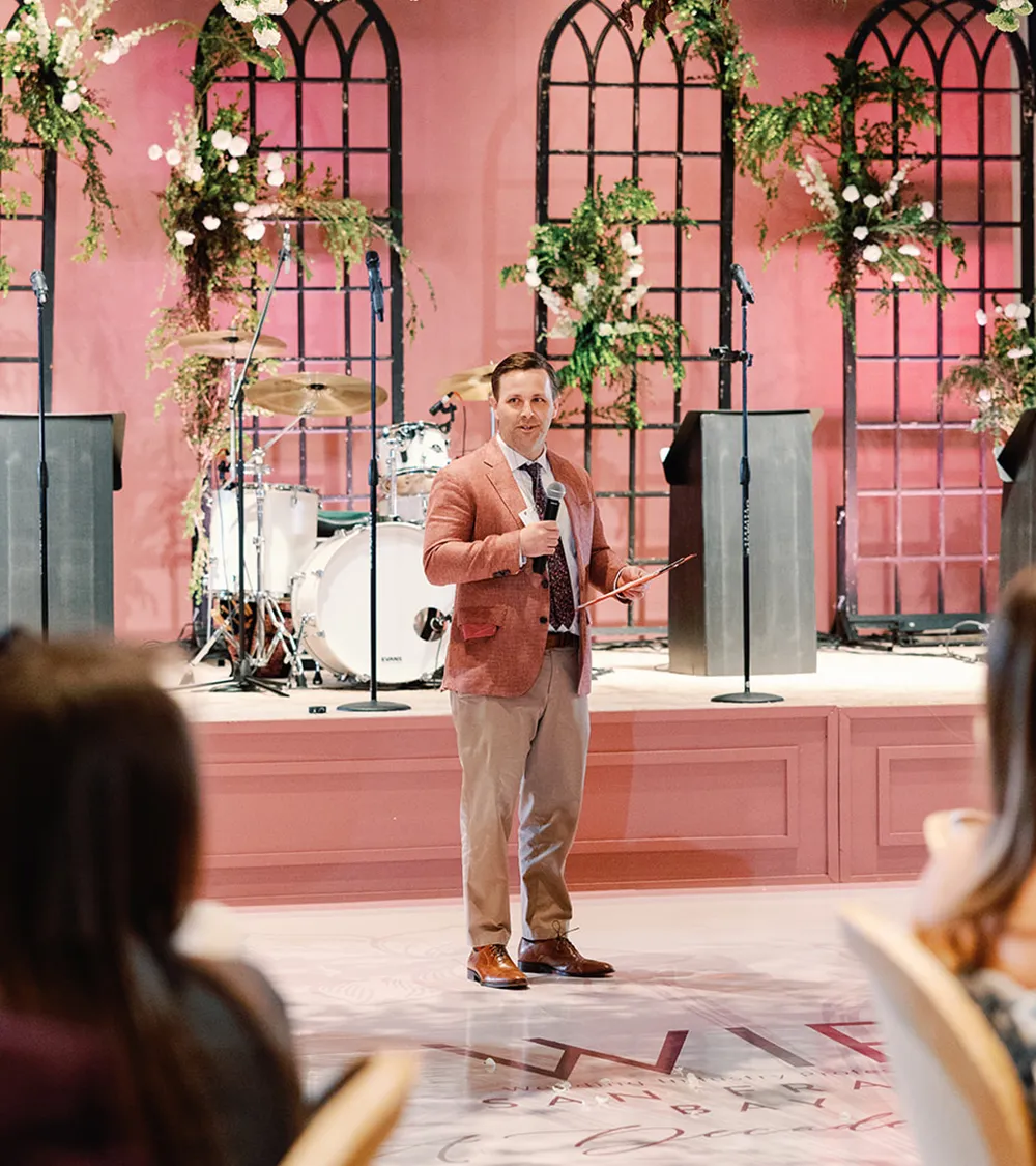 Emcee speaking at a decorated reception with a live band setup