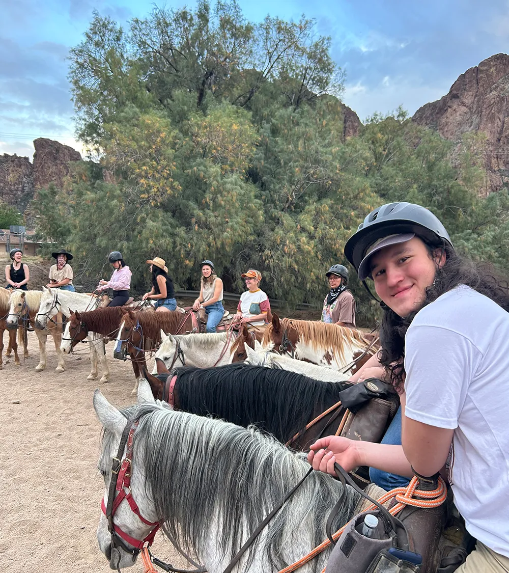 Team member smiling on horseback during a group outing