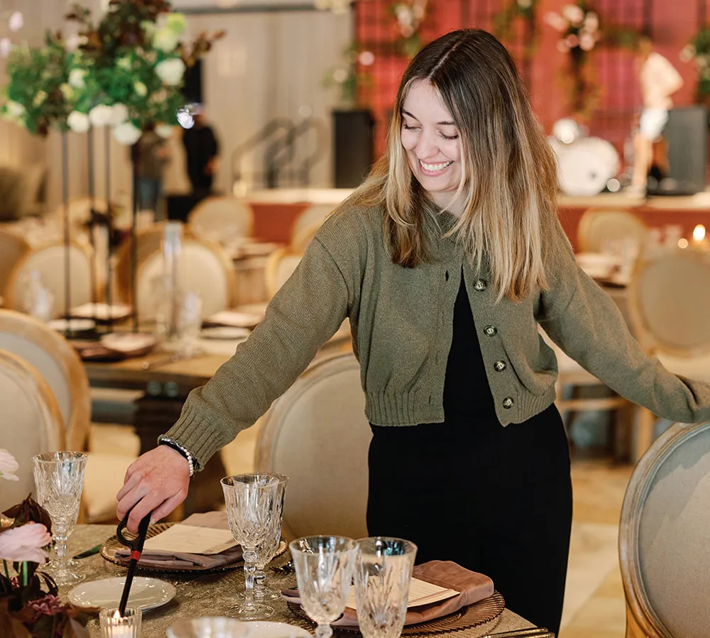 Event coordinator arranging place settings at an elegantly styled banquet table