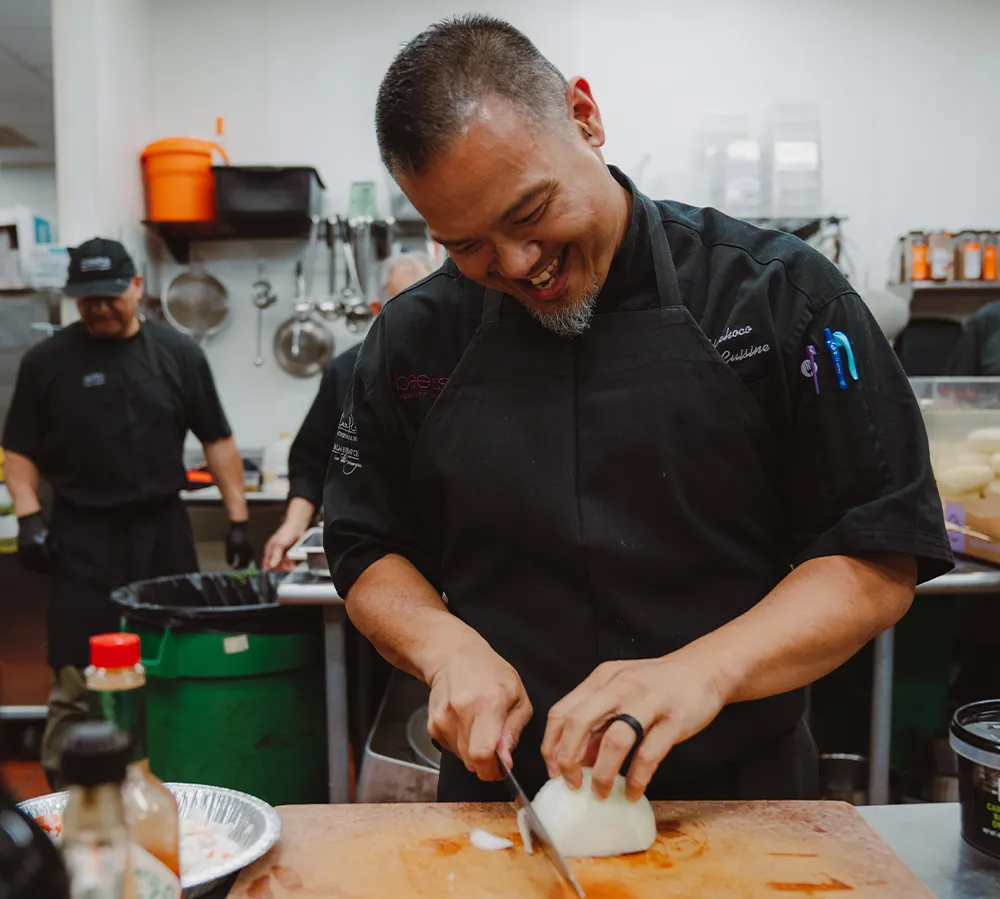 Chef slicing fresh ingredients on a cutting board in the Beets Hospitality kitchen