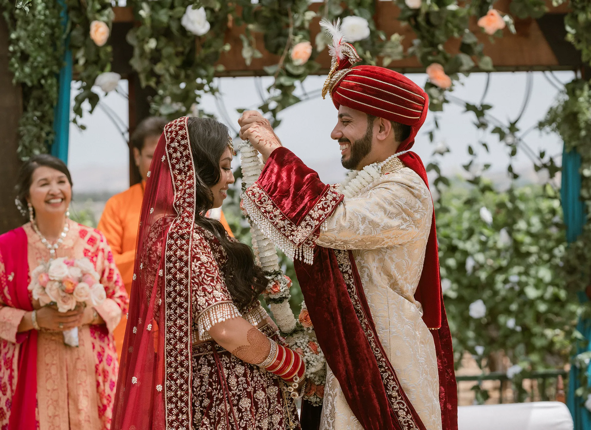 Couple exchanging garlands during a traditional Indian wedding ceremony outdoors